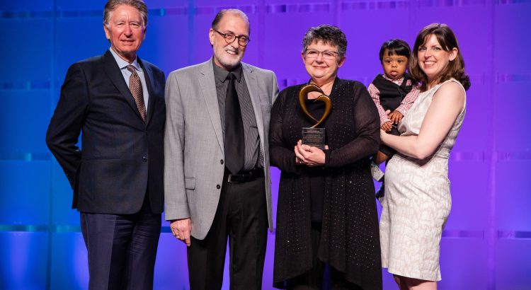 Synthia Cathcart accepting award with family on stage